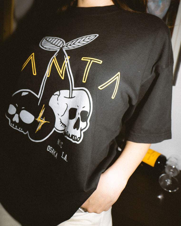 Person wearing a black t-shirt with a graphic design, standing indoors.